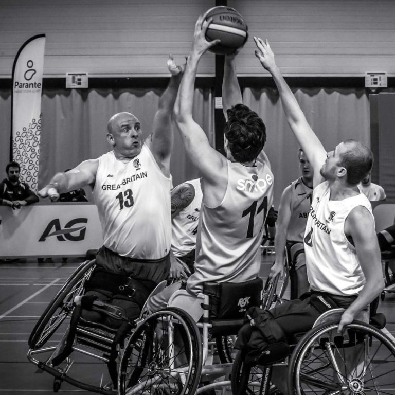 Mark Dutch Tilt Mark playing wheelchair basketball on tilt stopping a dutch player from shooting, while Kyle March tries to intercept the ball